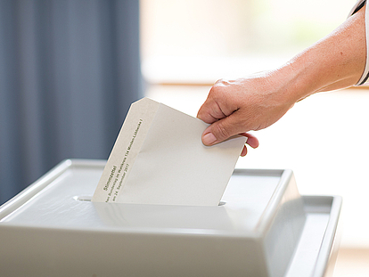 Stimmzettel wird in Wahlurne geworfen