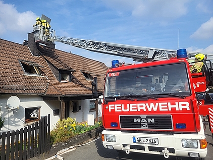 Eine Drehleiter, welche an einem Kamin angeleitert hat